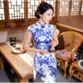 Woman wearing floor-length blue-and-white porcelain floral qipao in traditional setting