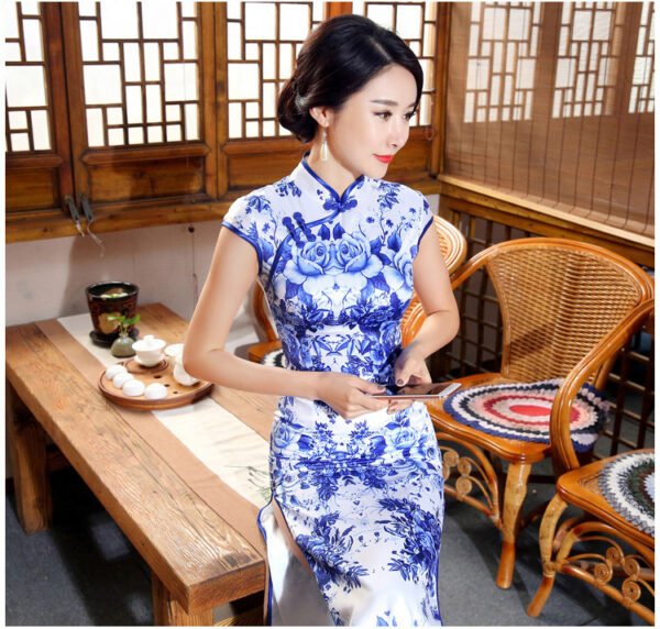 Woman wearing floor-length blue-and-white porcelain floral qipao in traditional setting